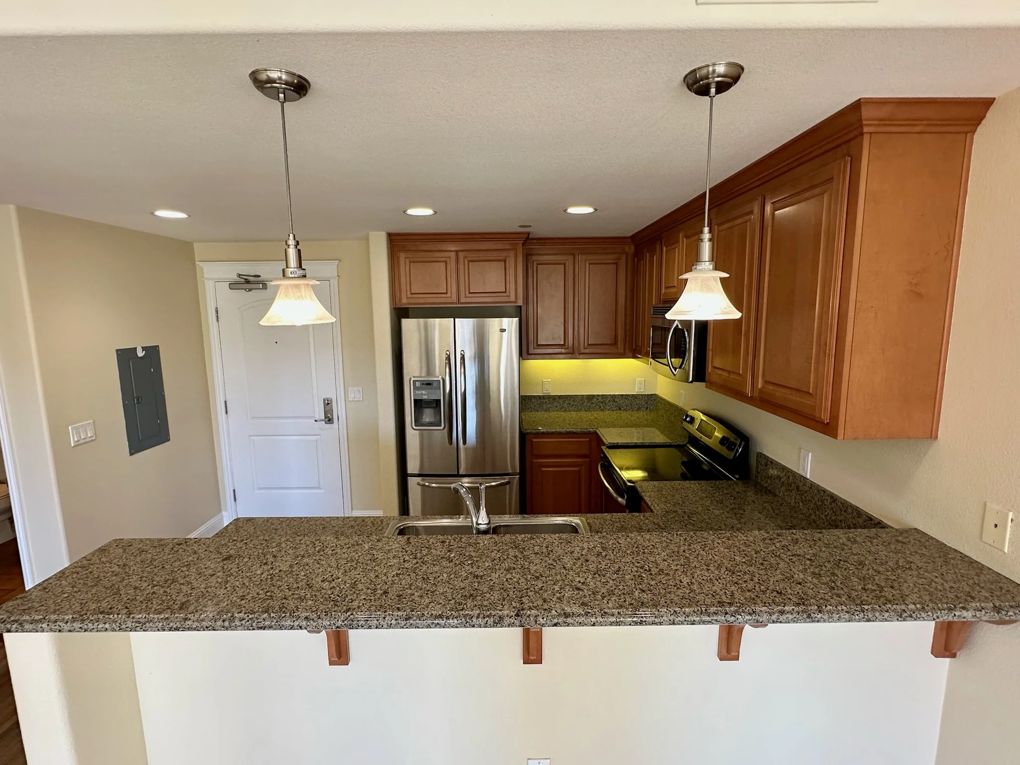 Kitchen with granite peninsula countertop and pendant lights in Unit 211